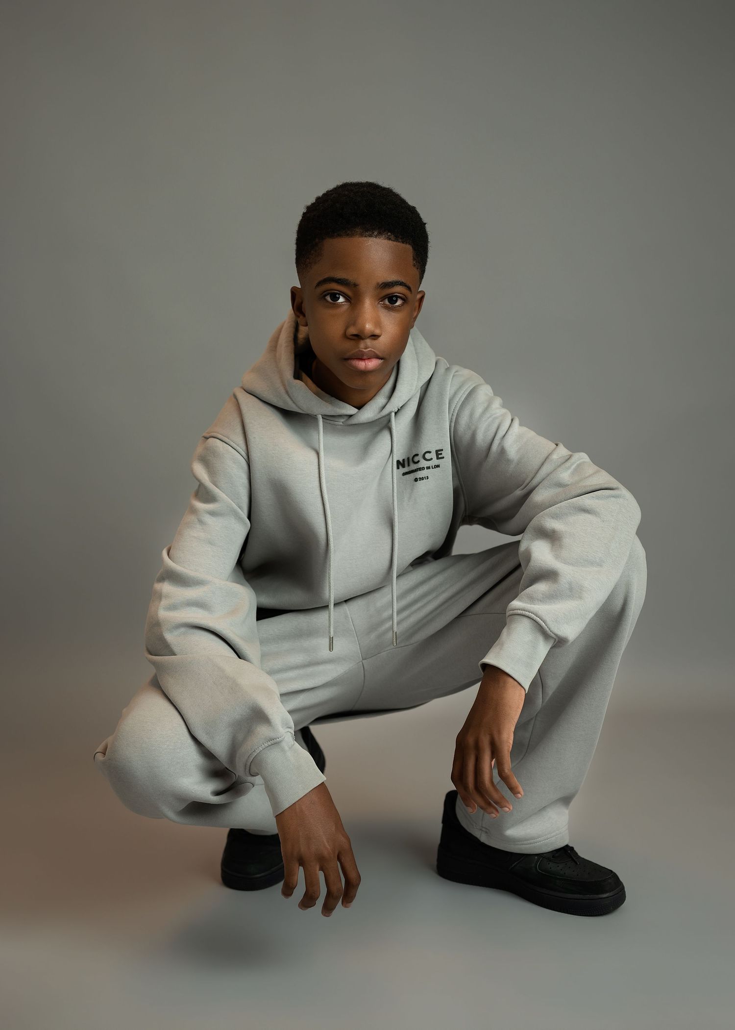 Children photography session in Gravesend Kent with boy in light outfit posing in studio on grey background