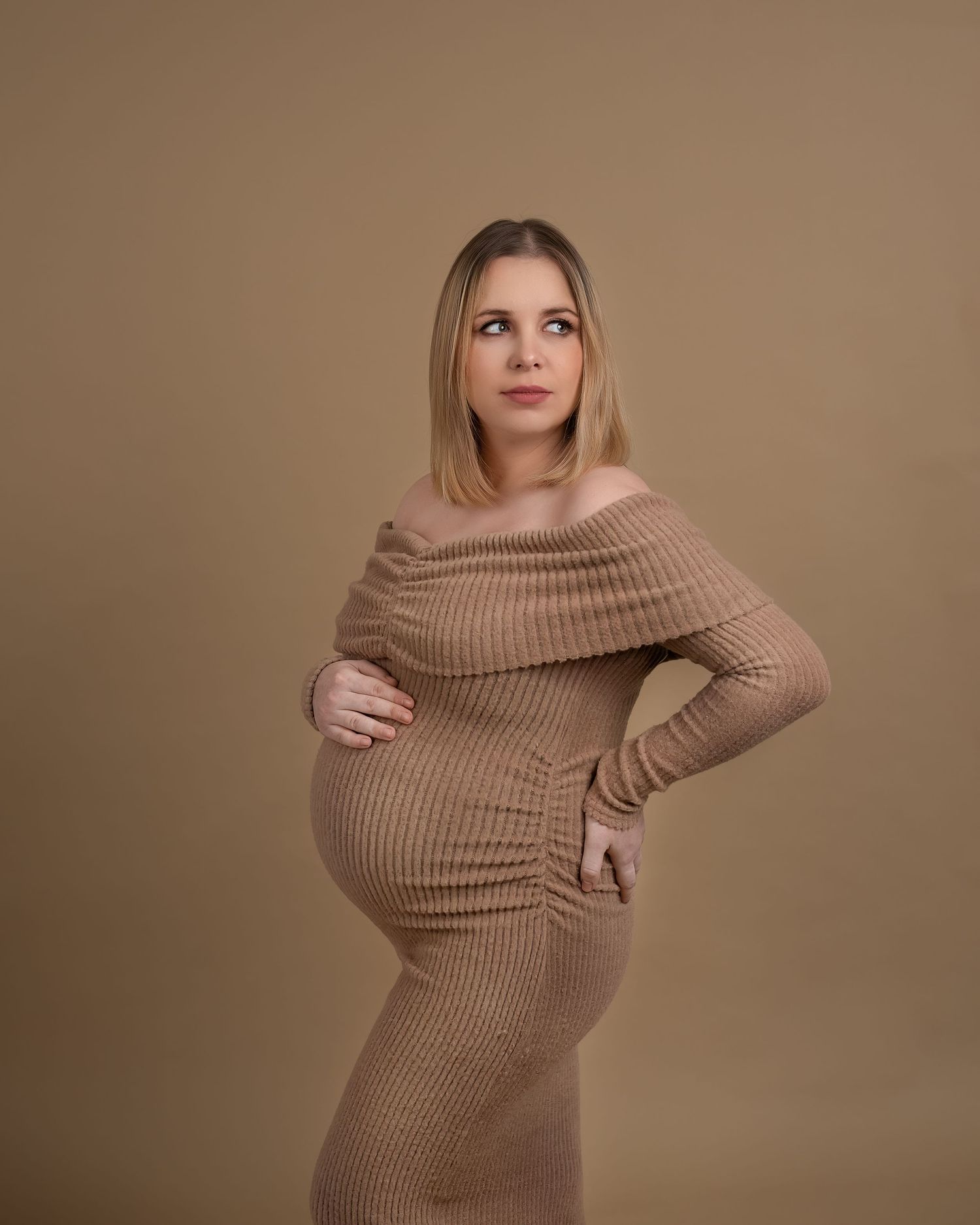 Maternity photography session in Gravesend Kent with pregnant woman in fitted beige dress holding baby bump