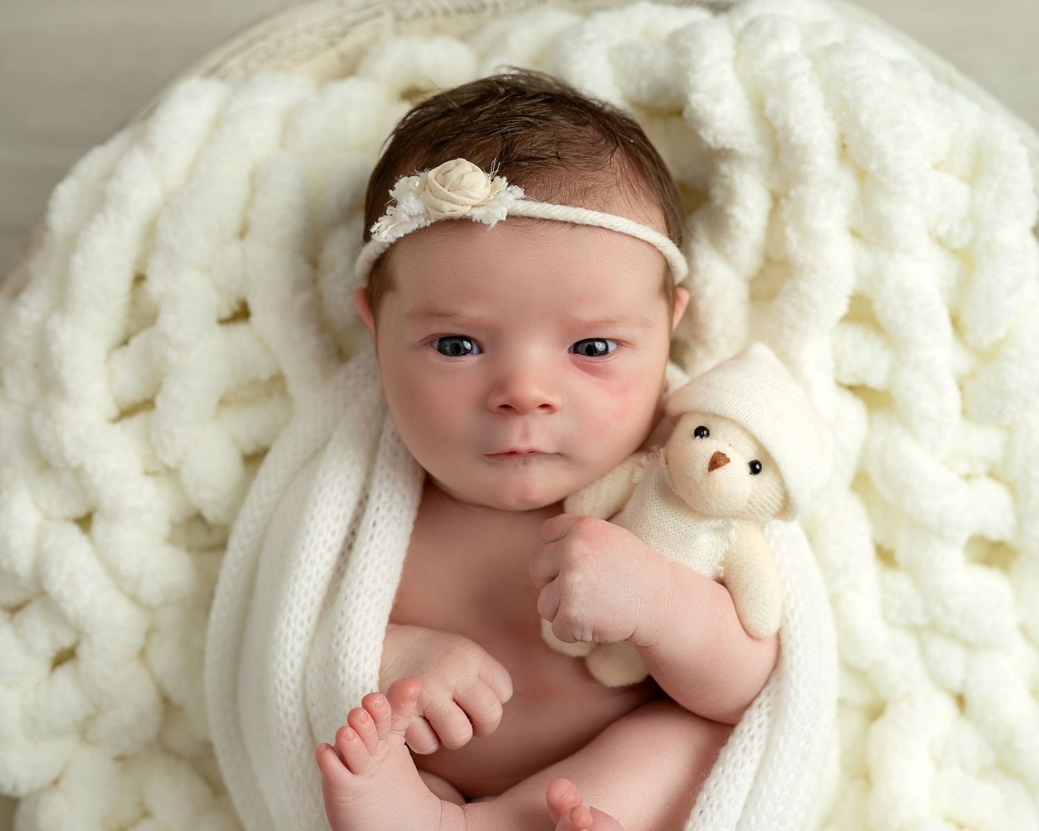Newborn photography session in Gravesend Kent with baby wrapped in soft blanket lying on textured background
