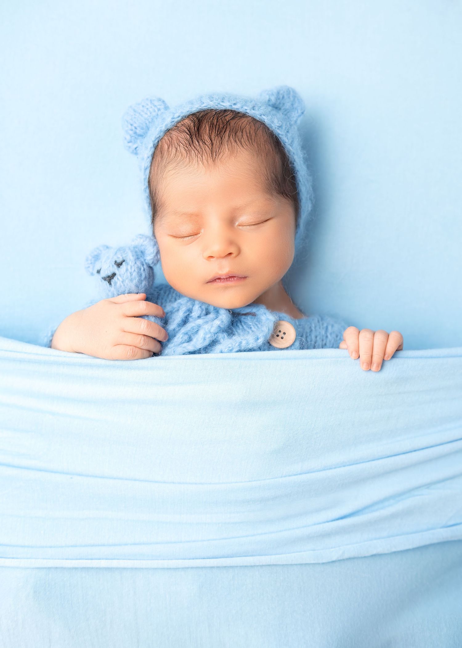 Newborn photoshoot in Gravesend Kent with baby wrapped in blue fabric sleeping in studio
