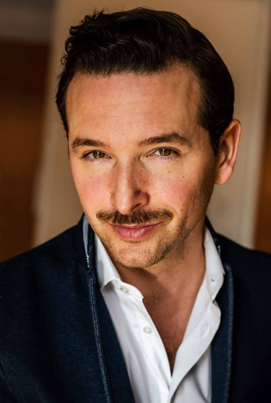 Business headshot of man with mustache in navy blazer and white dress shirt