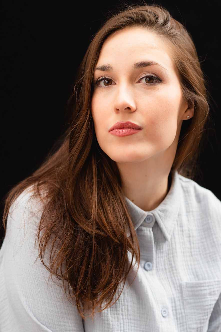 Corporate headshot of woman with wavy brown hair and natural makeup in white blouse