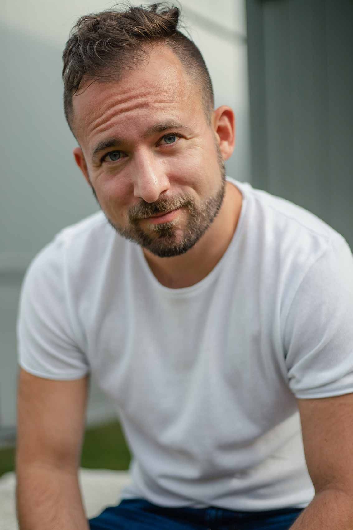 Natural light portrait of smiling man in white t-shirt with trimmed beard