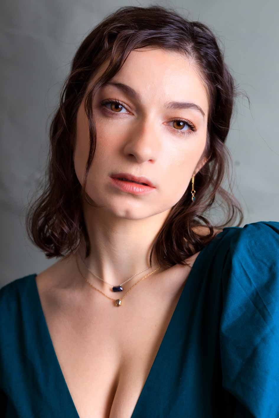 Natural light headshot of brunette woman wearing turquoise top and delicate necklaces