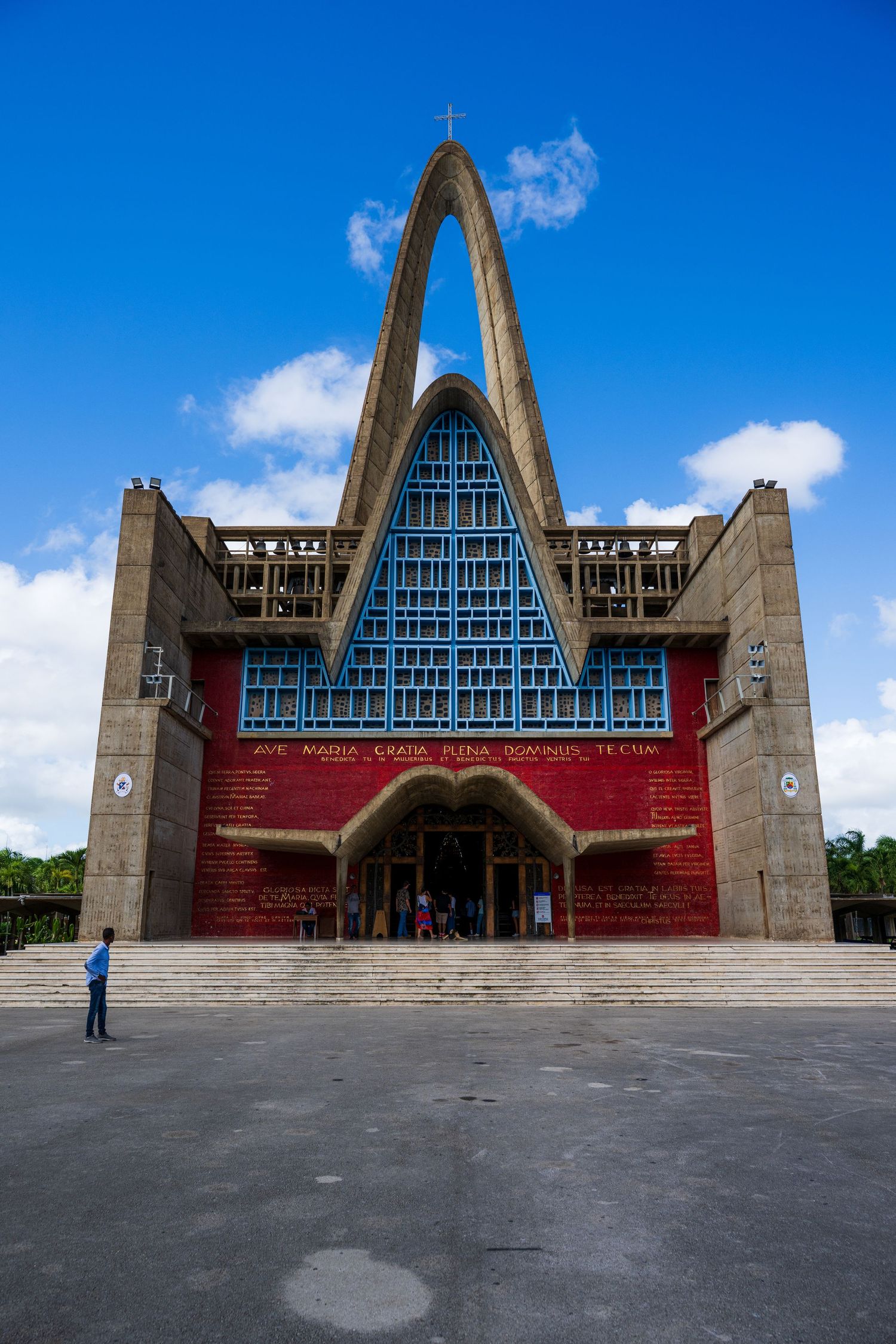 Basilica of Our Lady of Altagracia, a striking modern Catholic church with red facade and tall concrete arch in Dominican Republic.