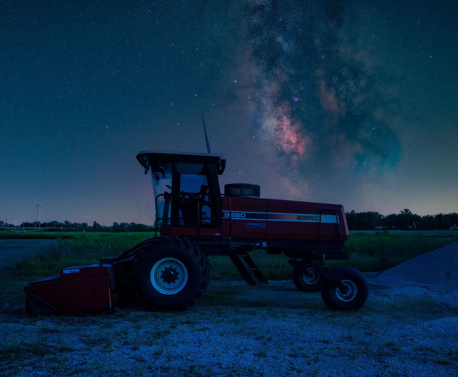 Red tractor parked in a field under a stunning Milky Way galaxy night sky with vibrant stars and cosmic glow.