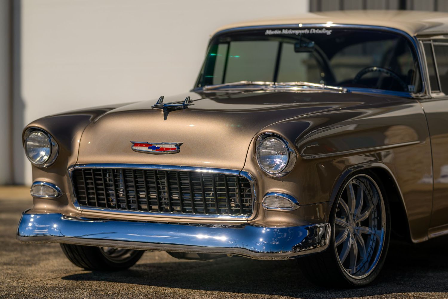 A restored 1955 Chevrolet Bel Air in bronze with chrome accents and custom wheels on display.