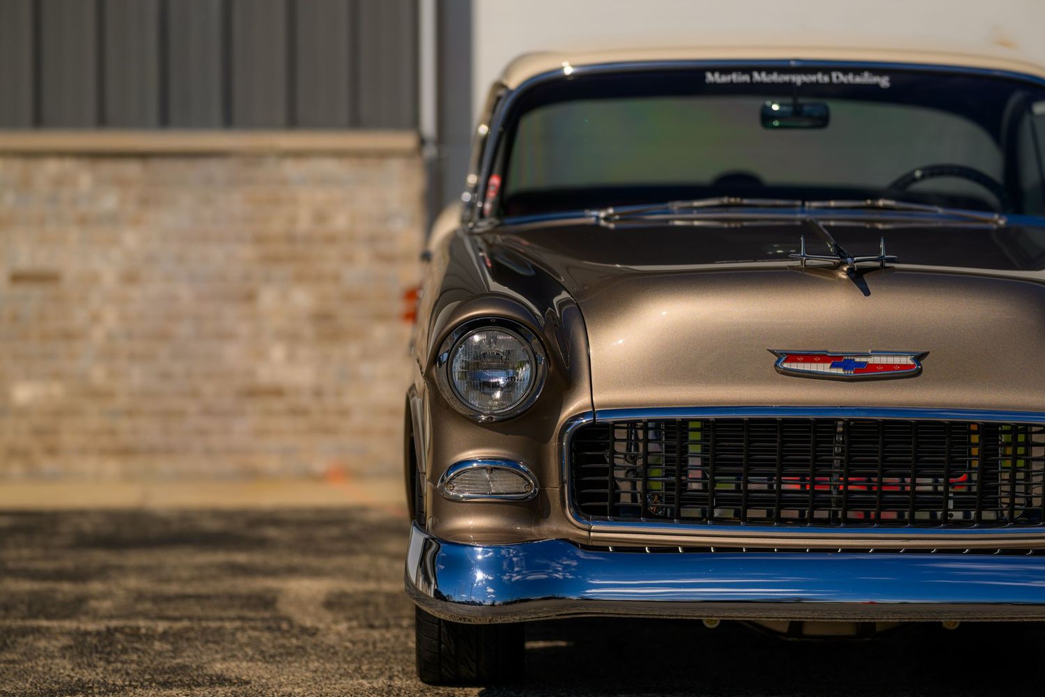 A restored 1955 Chevrolet Bel Air in bronze and blue, showcasing its iconic chrome grille and classic front-end design.