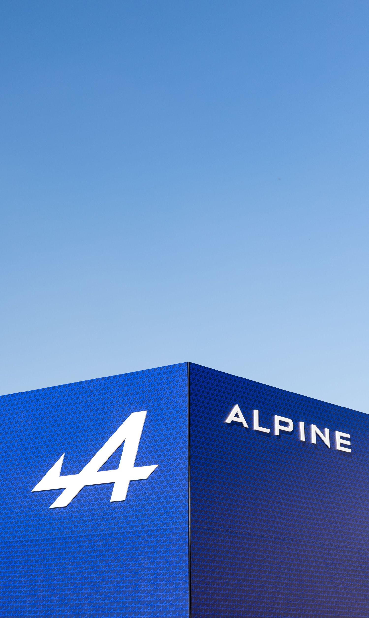 Alpine car brand blue building exterior with iconic A logo and ALPINE wordmark against clear blue sky.