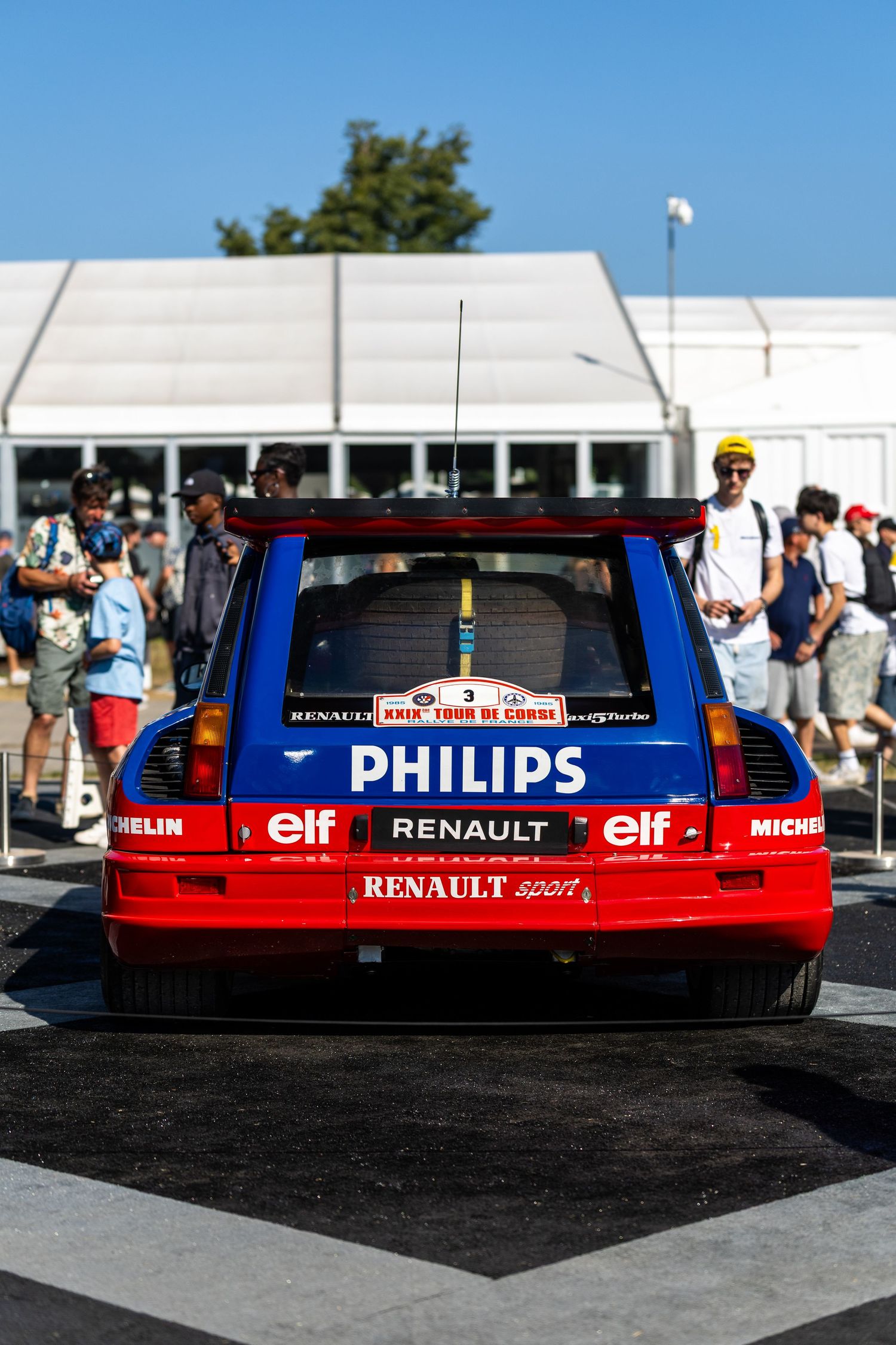 Rear view of a Renault Sport rally car with Philips and Elf sponsorship at an outdoor motorsport event.