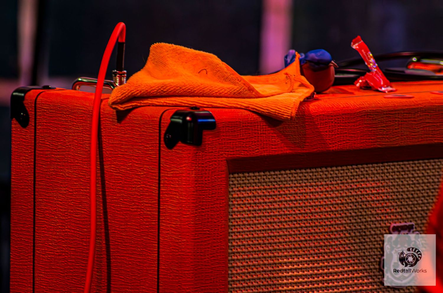 Orange guitar amplifier with a towel draped over it on a concert stage.