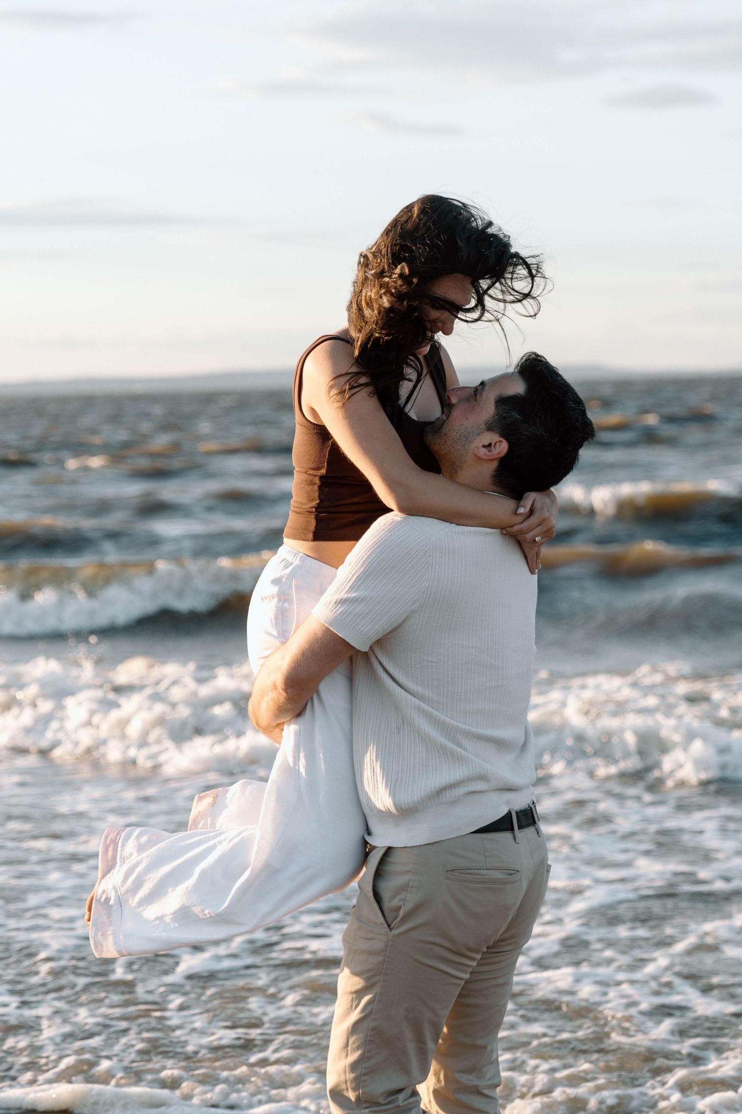 A man spinning his wife on a beach