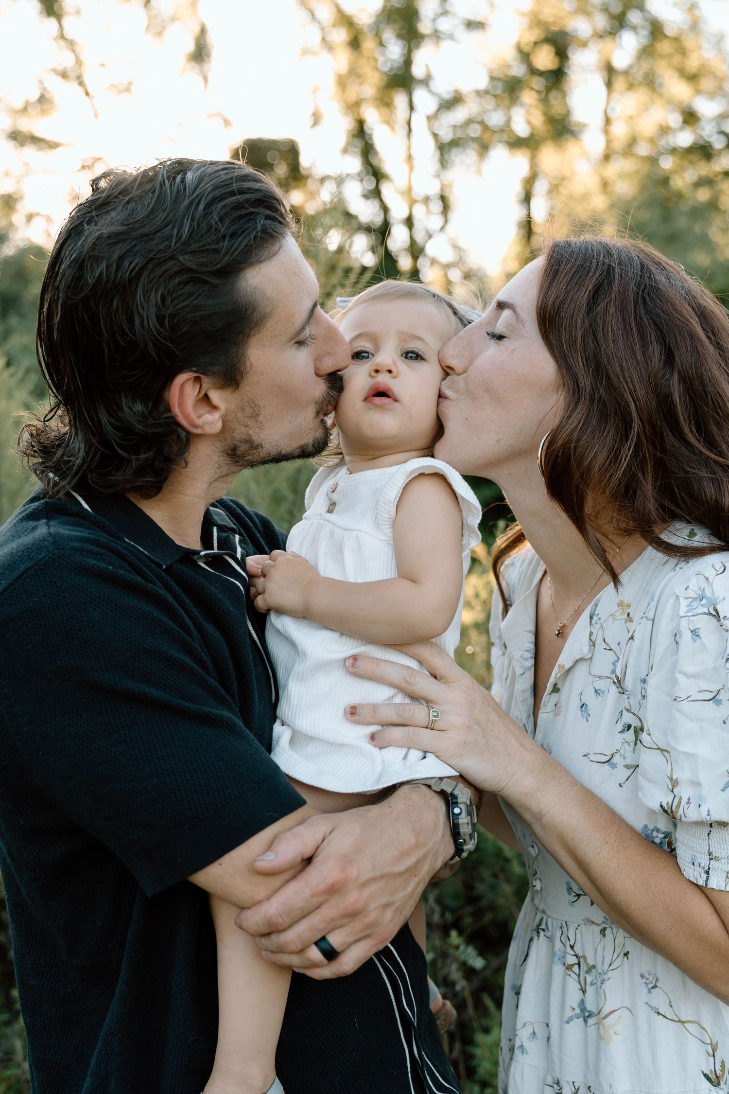 Mom and dad kissing their little girl