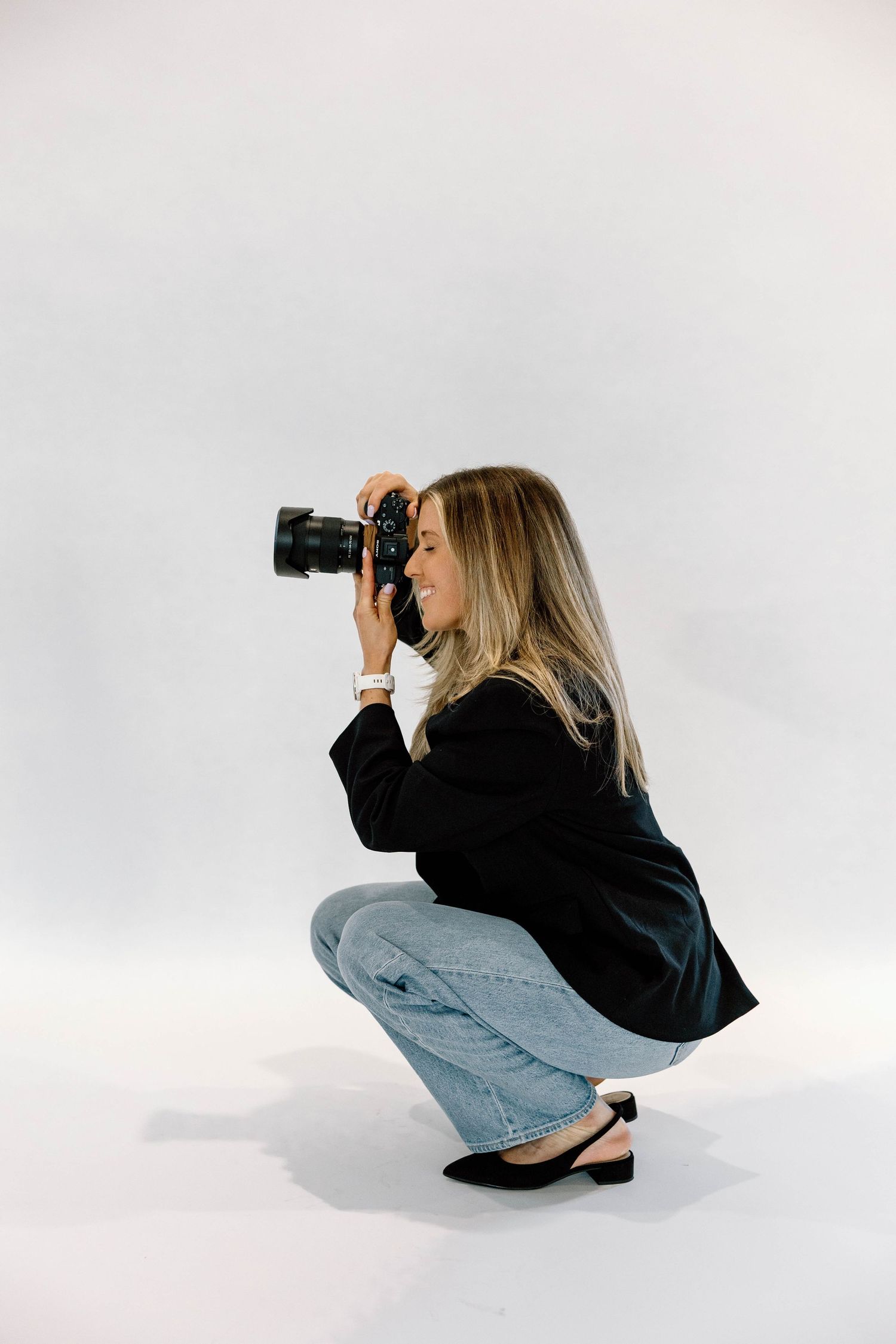 A photographer crouched down taking a photo with her camera