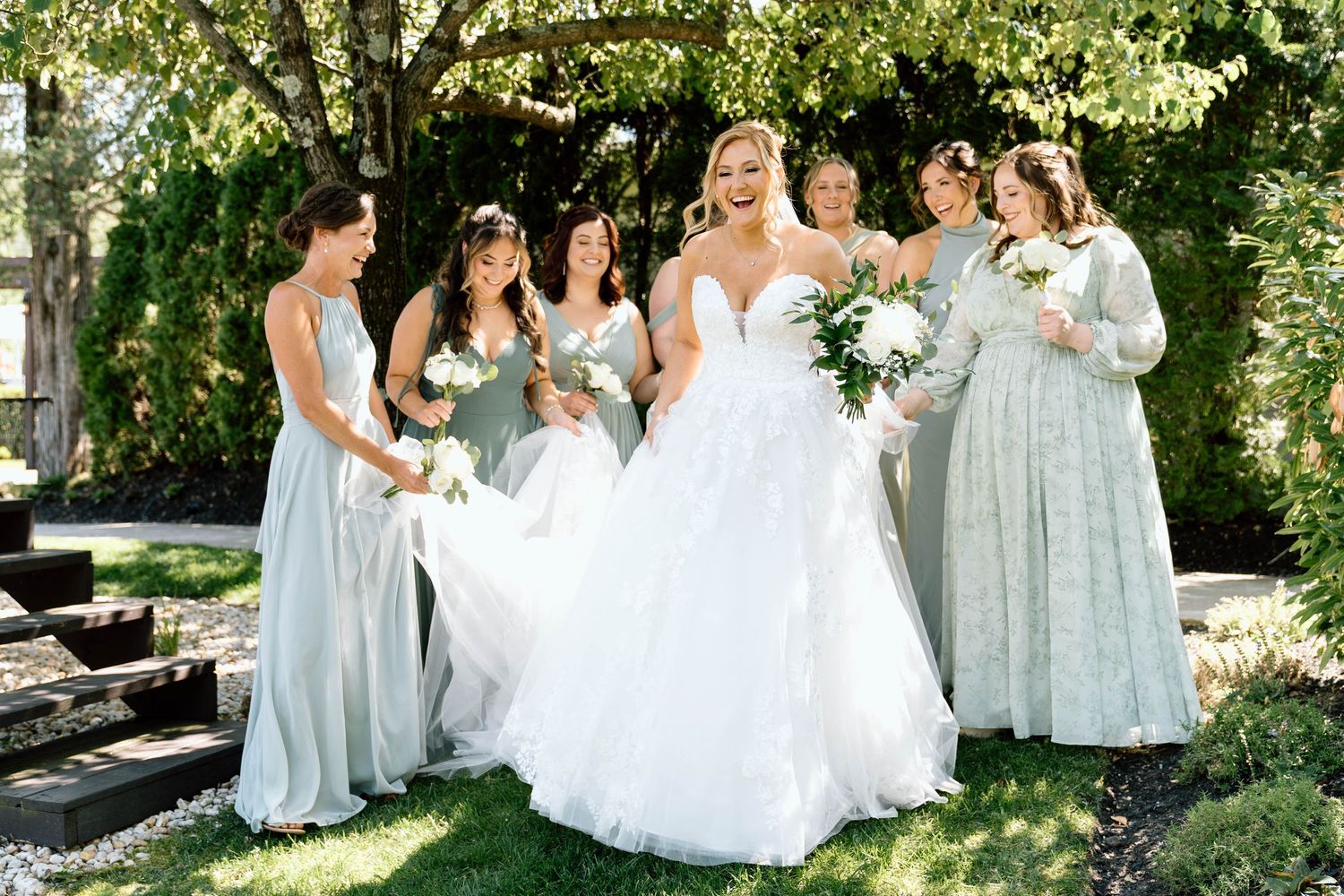Bride laughing as her bridesmaids carry the train of her dress