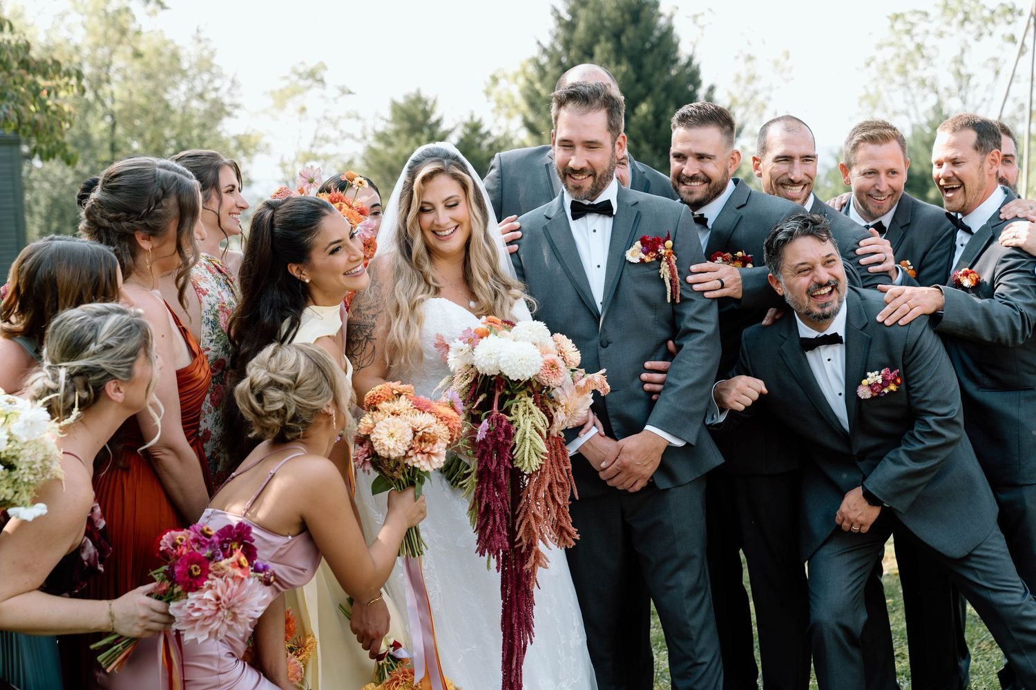 Bridal party laughing and hugging the bride and groom