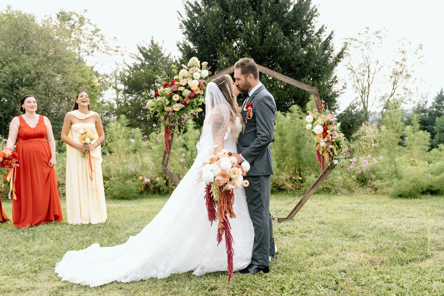 Bride and groom kissing in front of a wood display with wildflowers