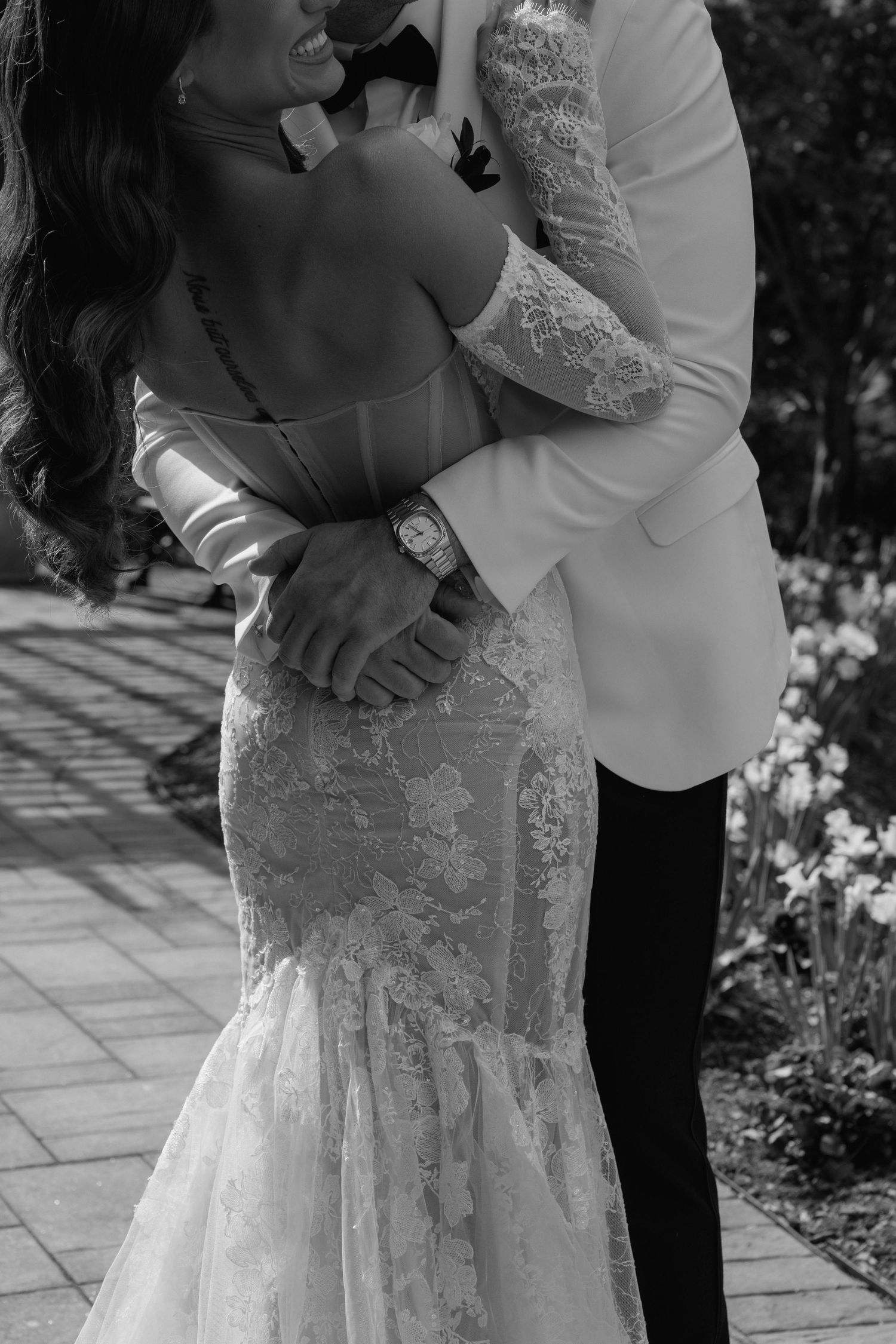 Close-up of a groom hugging his bride in a mermaid lace dress