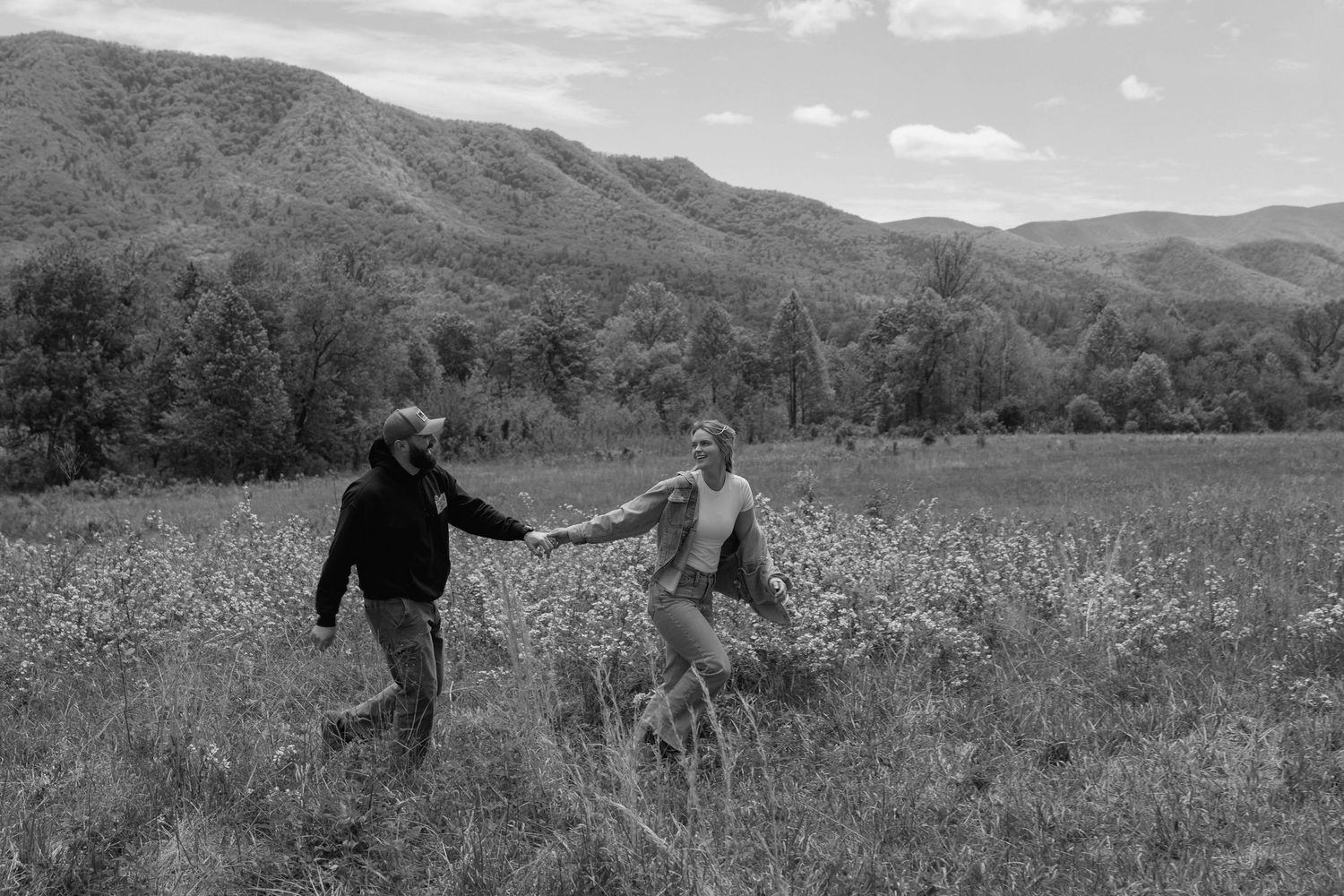 Couple running through a field holding hands
