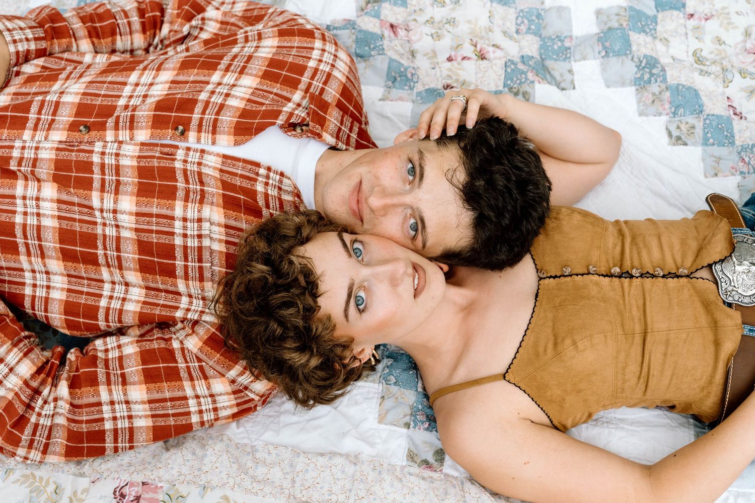 Man and woman lying on a picnic blanket looking up at the camera