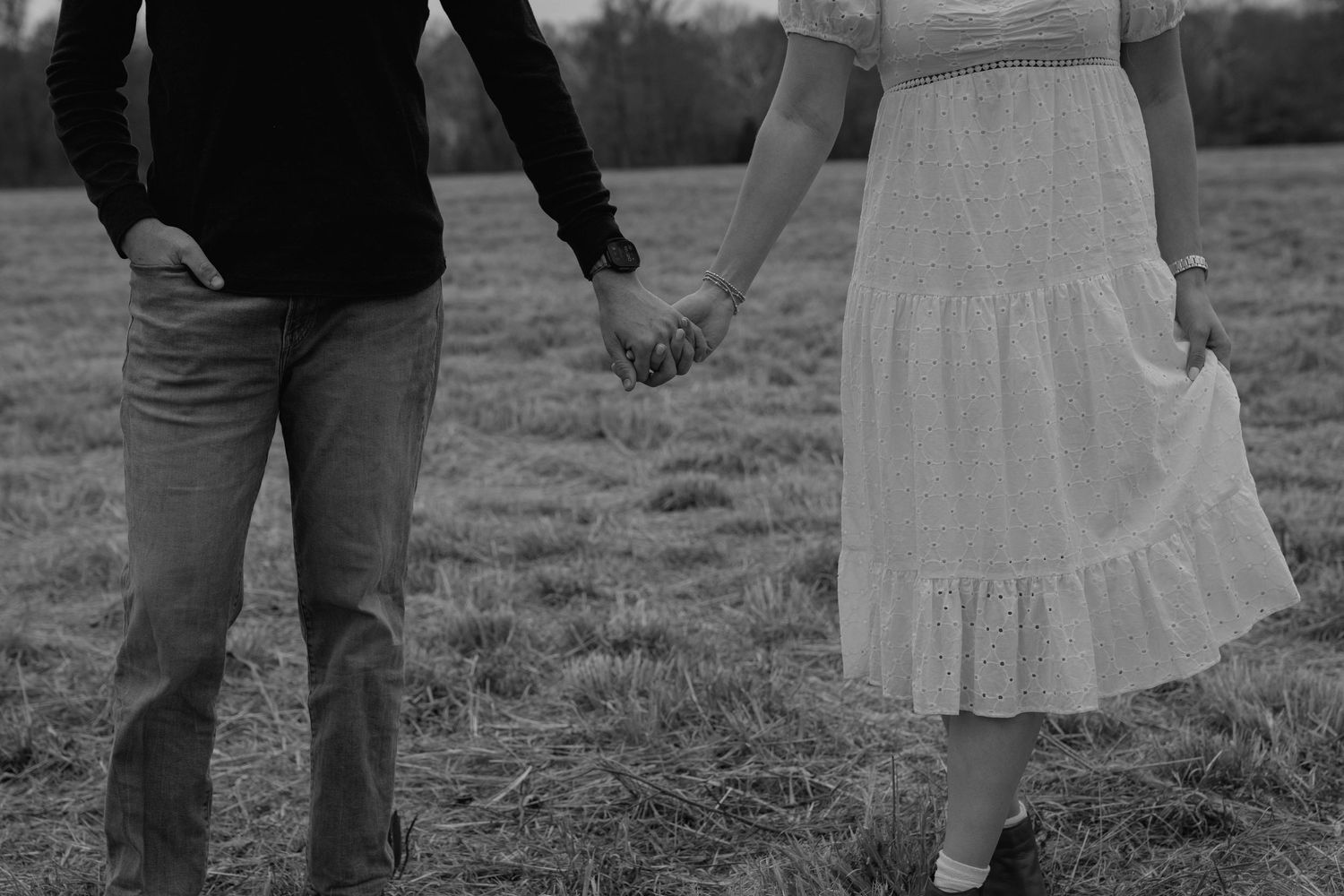 Close-up image of a couple holding hands in a field