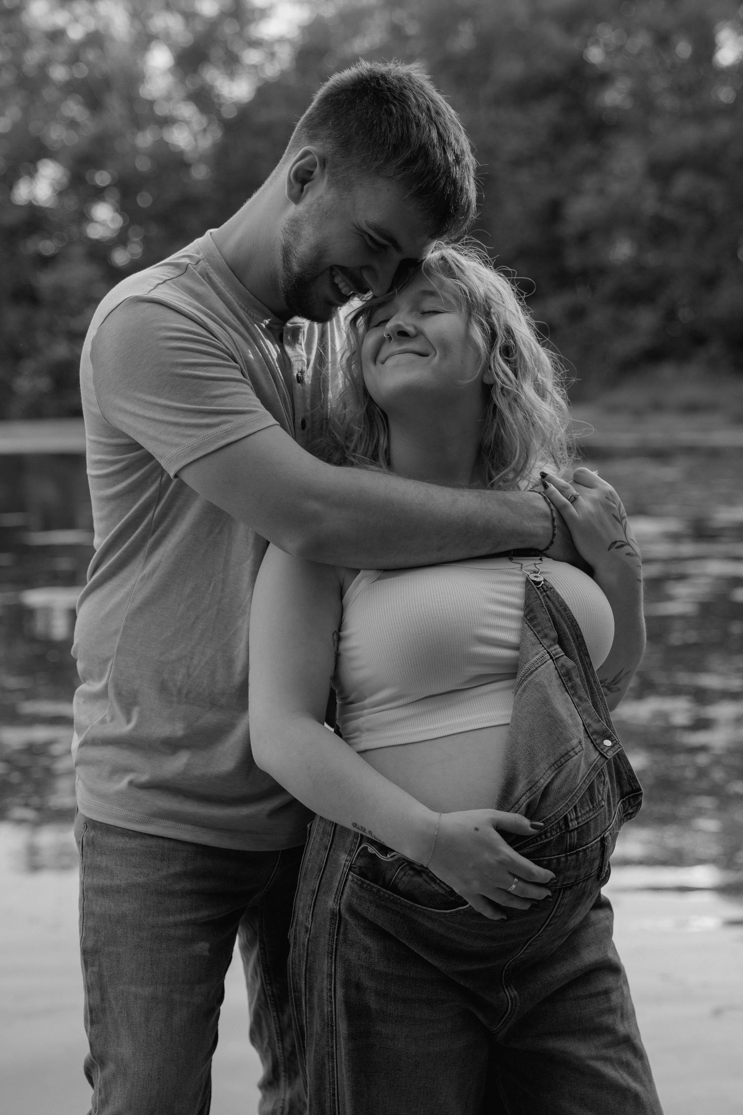 Man hugging a woman while her hand rests on her pregnant belly