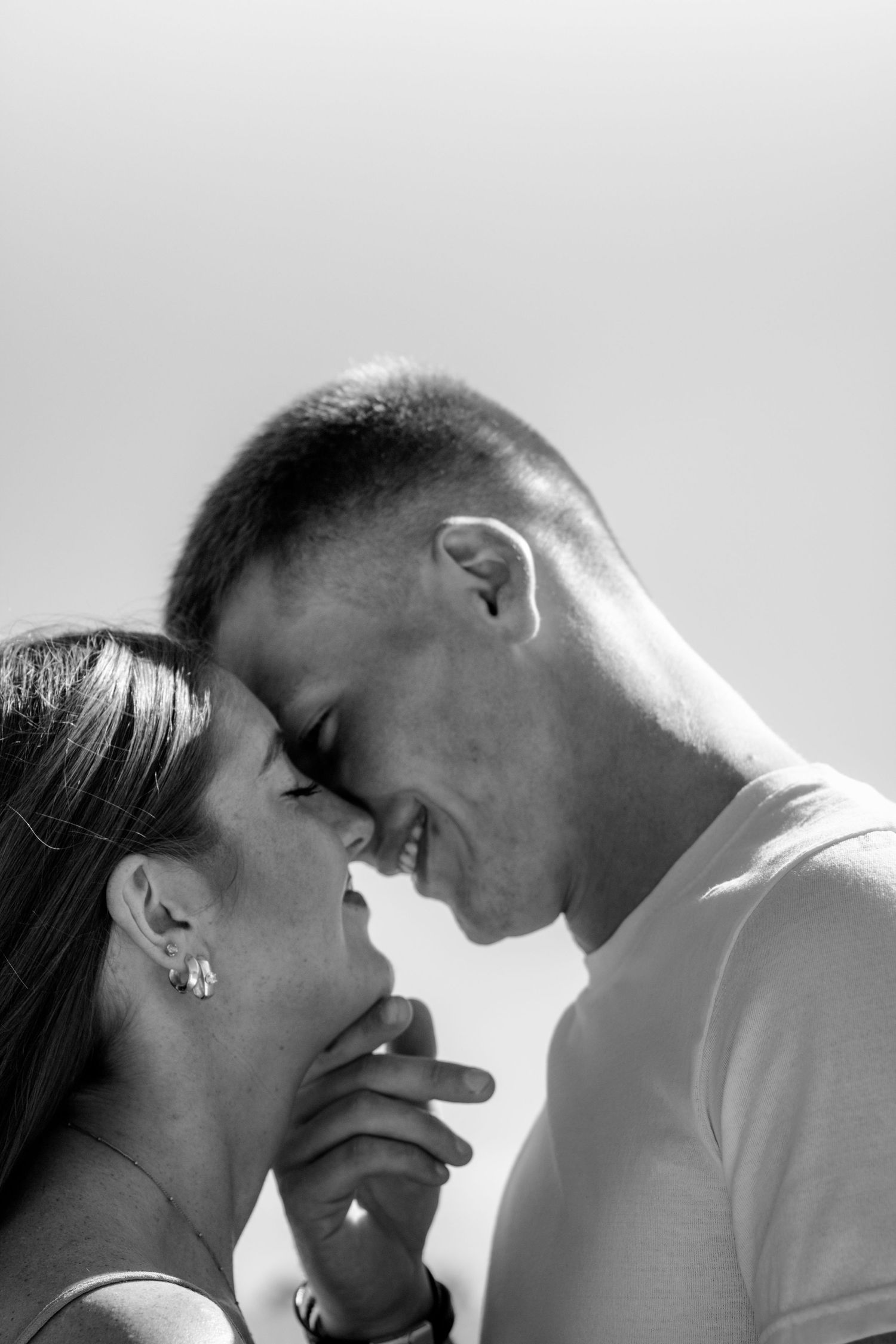 Black and white photo of a romantic couple smiling and touching foreheads together in an intimate moment.