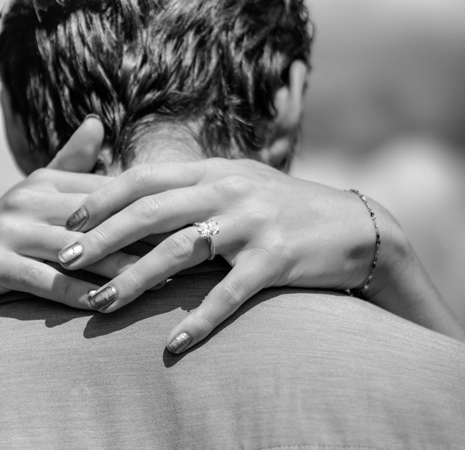 Black and white photo of a woman resting her hand on a man's shoulder, wearing a ring and bracelet.