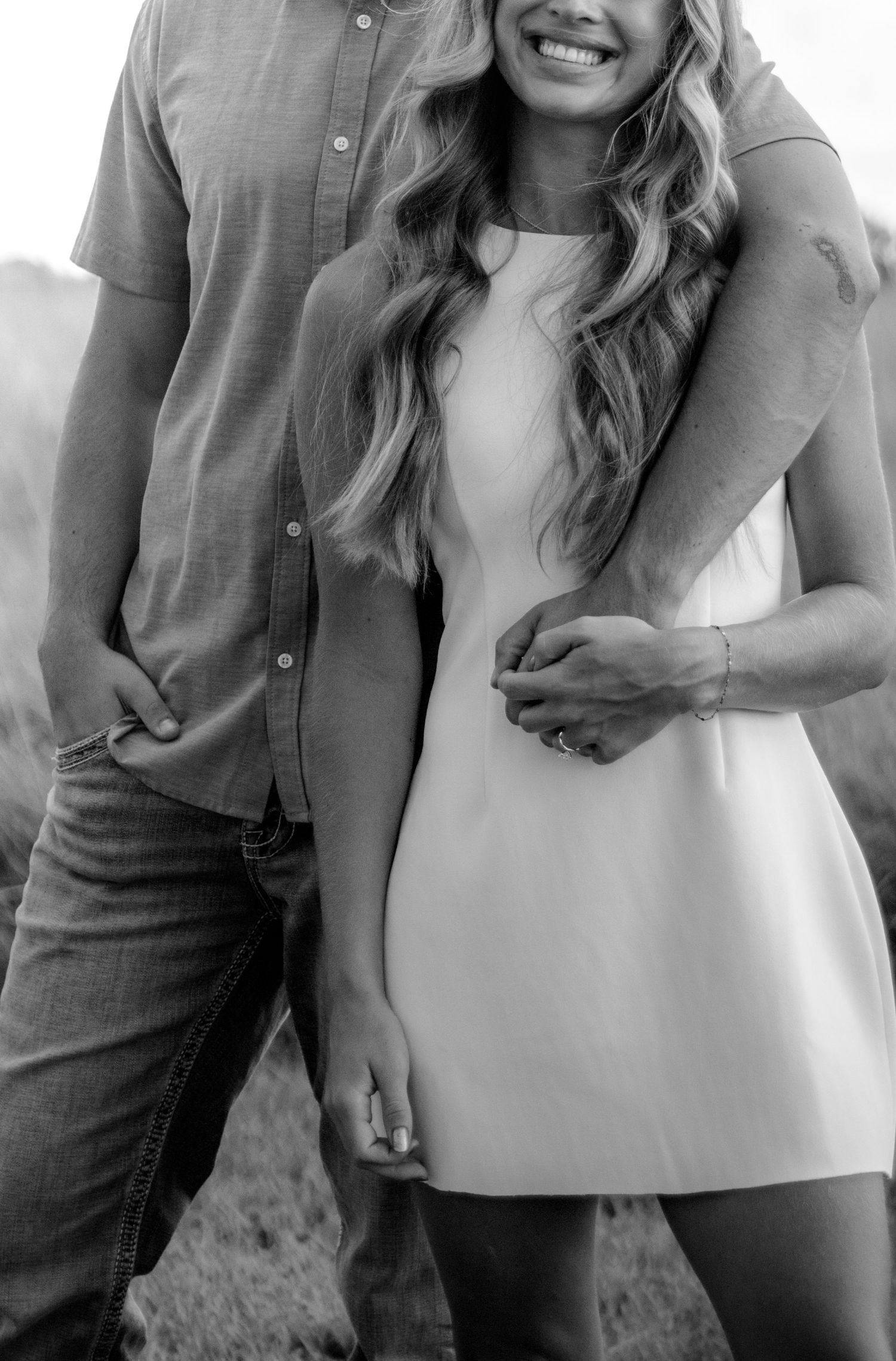 Black and white photo of a couple embracing, woman in white mini dress holding hands with man.