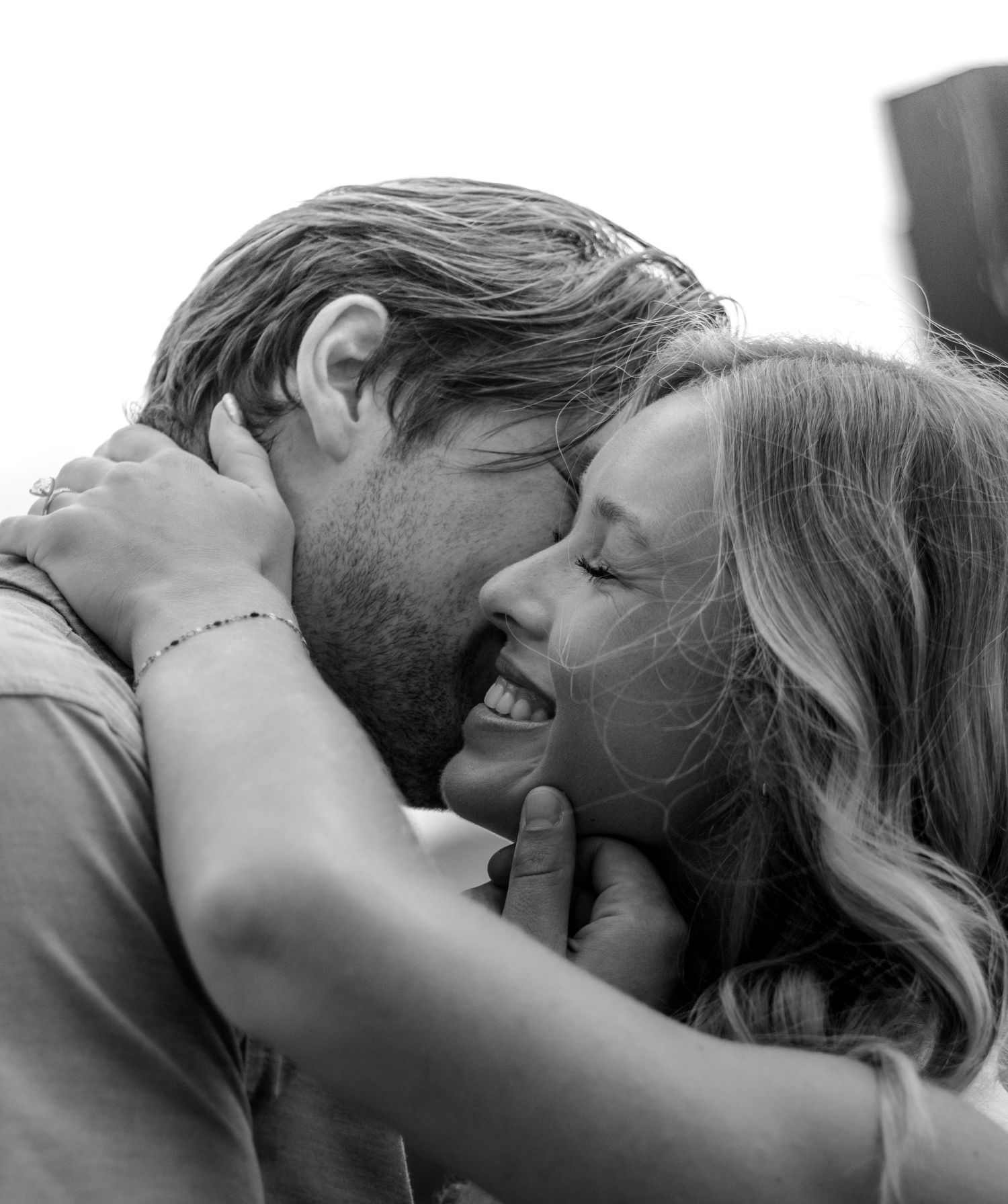 Black and white photo of a couple embracing and smiling, sharing a tender romantic moment.