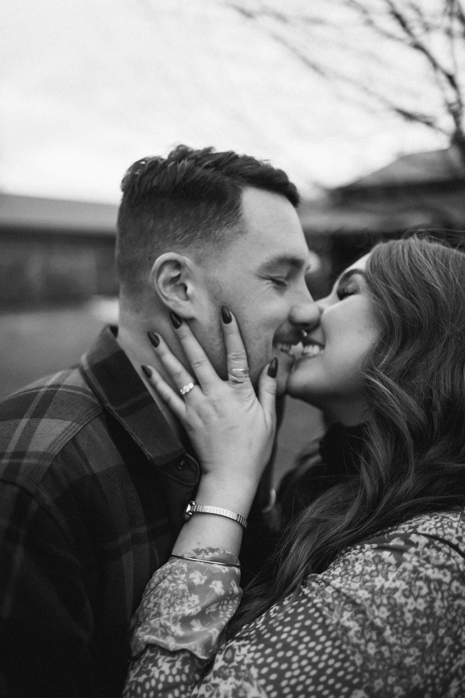 A romantic black and white portrait of a couple sharing an intimate kiss outdoors.