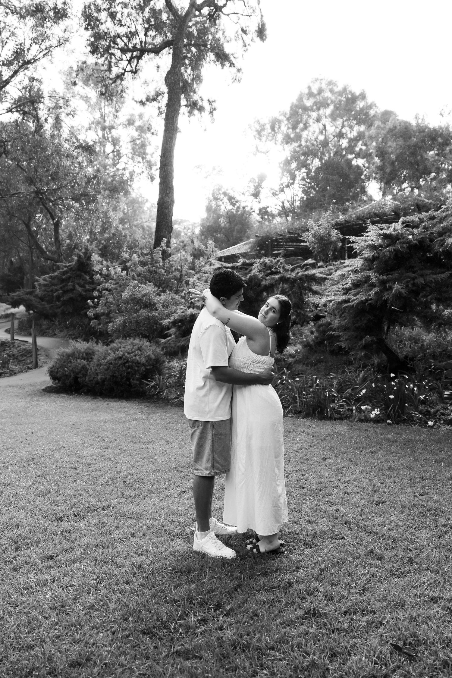 Black and white photo of a couple embracing and hugging in a beautiful garden park.
