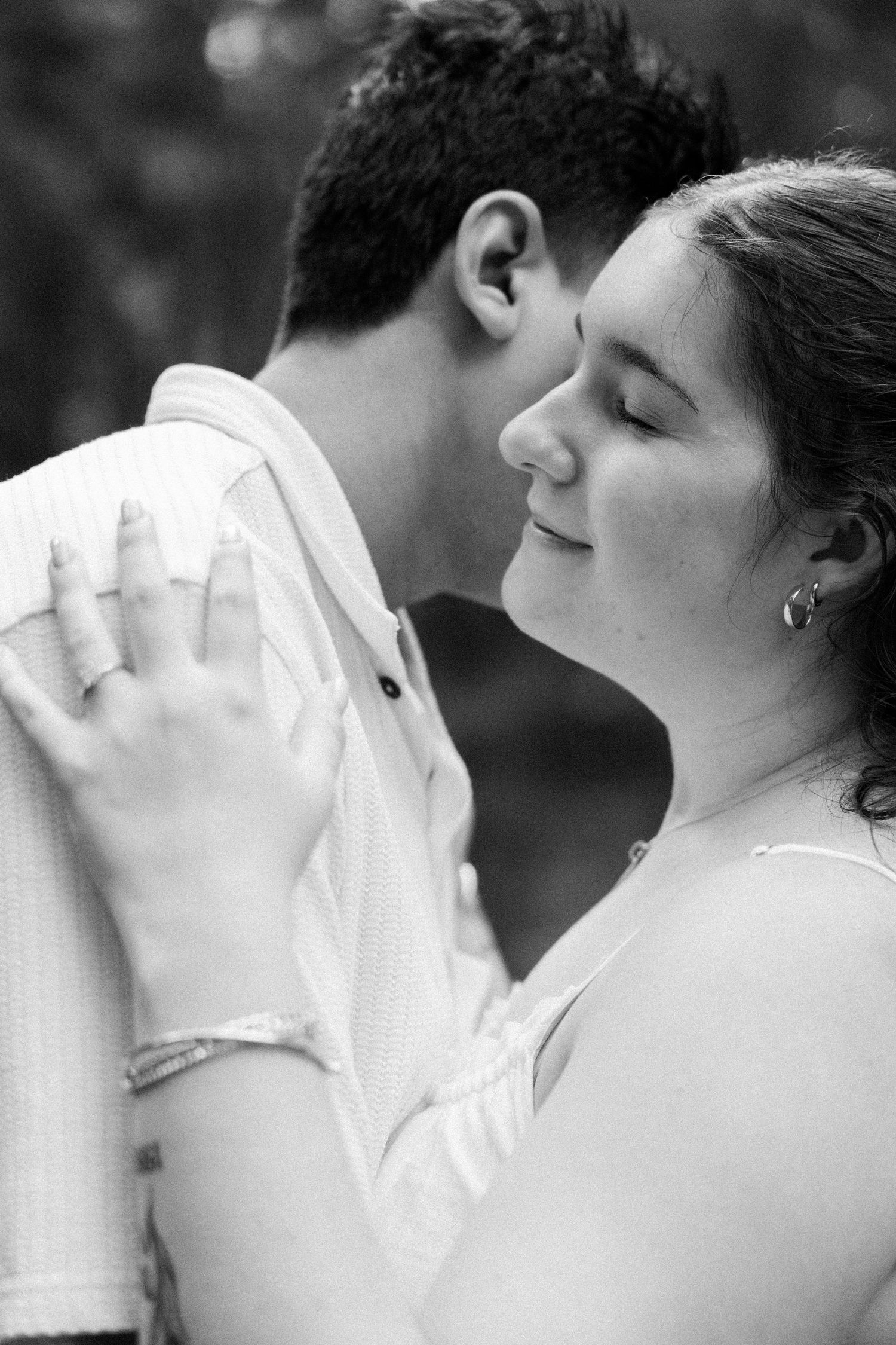 Black and white close-up of a couple in an intimate embrace, woman smiling peacefully with eyes closed.