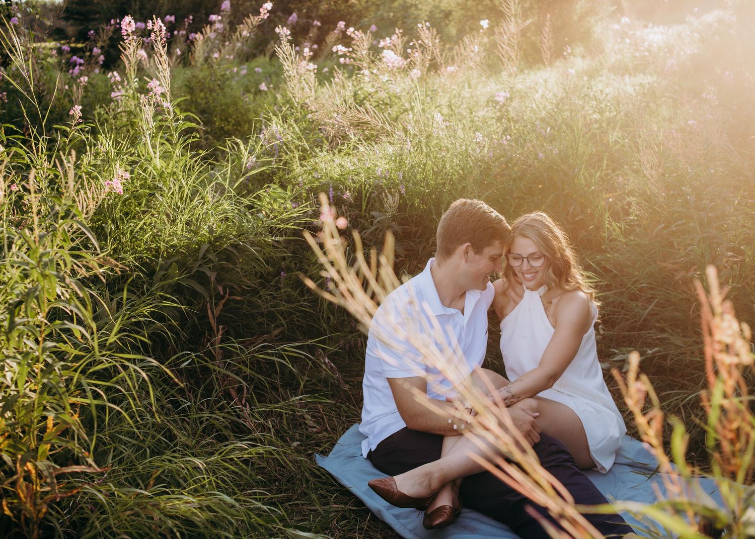 Couple sitting together in a field of tall grass during an outdoor portrait session
