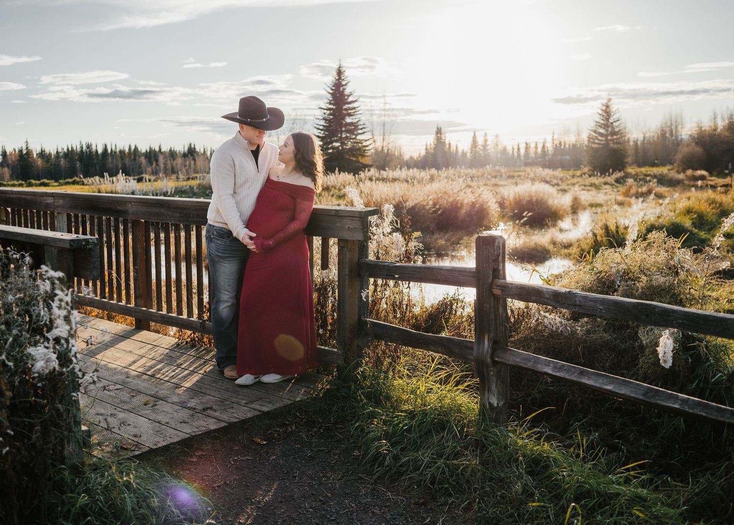 Expecting couple embracing on a wooden overlook surrounded by autumn scenery during a maternity session