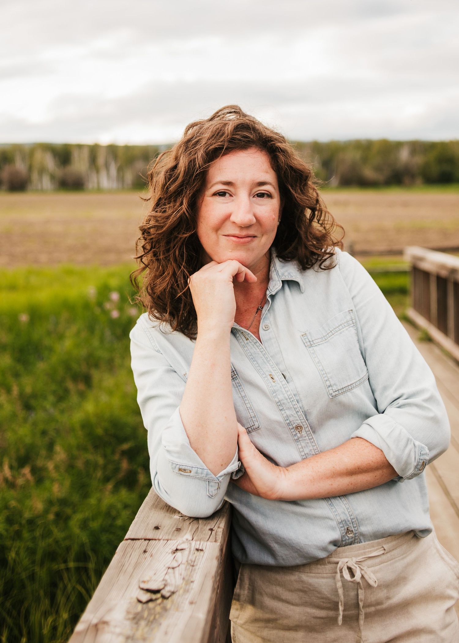 Portrait of a photographer leaning on a wooden fence outdoors