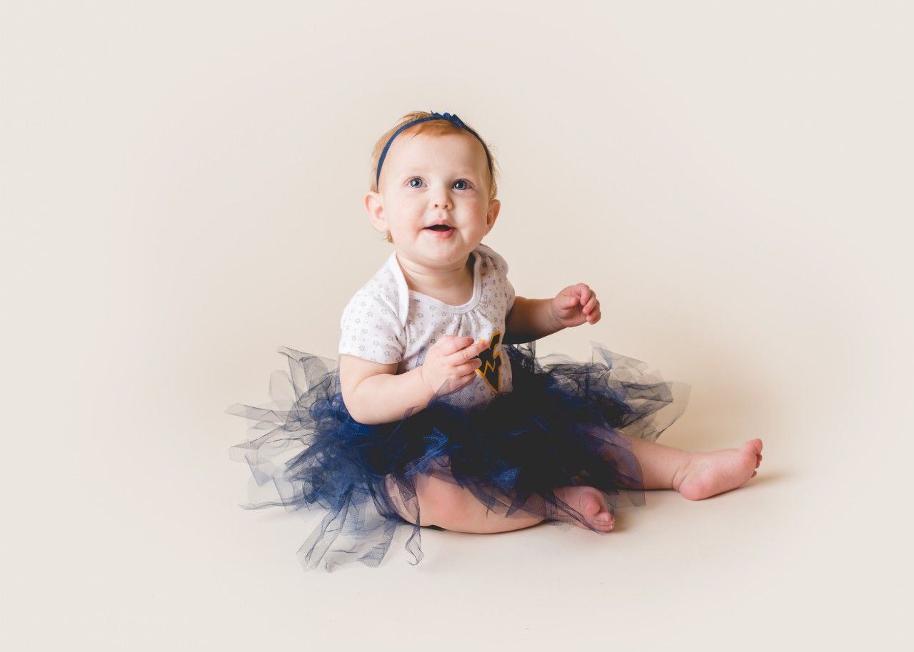 Smiling baby sitting in a blue tulle tutu during a portrait session