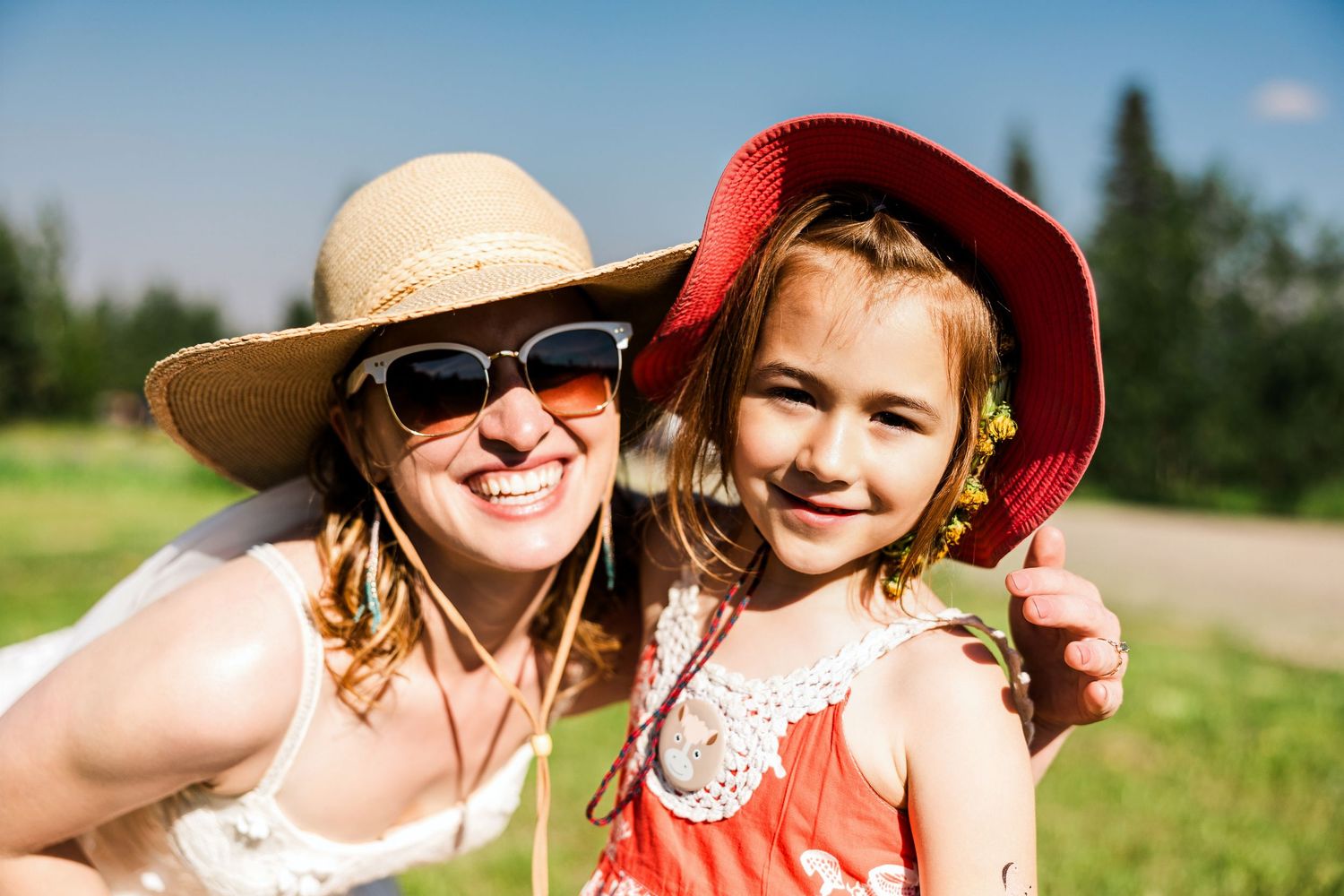 Summer day portrait with sun hats against green outdoor background.