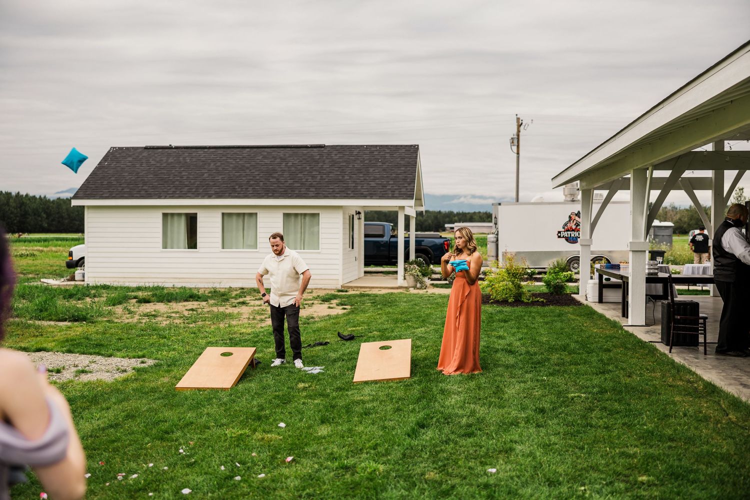 Wedding guests playing cornhole lawn game outside during reception festivities.