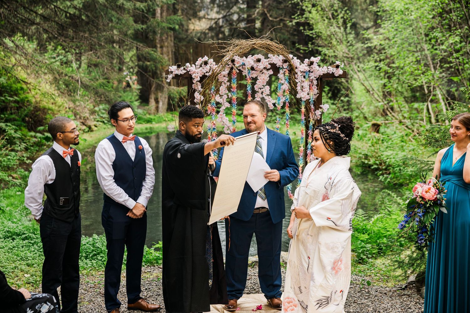 Wedding party stands in formation during outdoor forest ceremony.