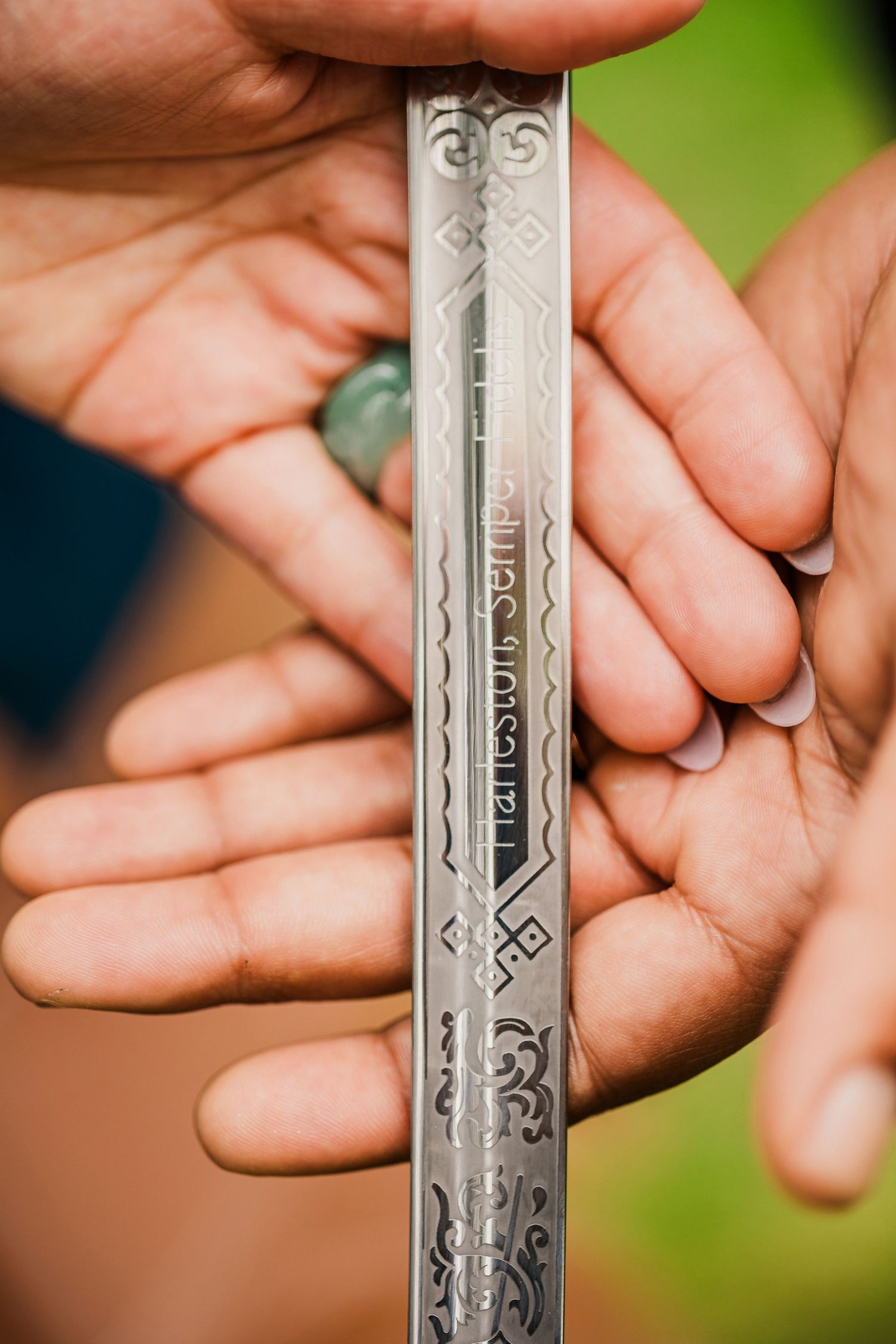 Close-up of hands holding an ornately engraved metal object with decorative patterns.