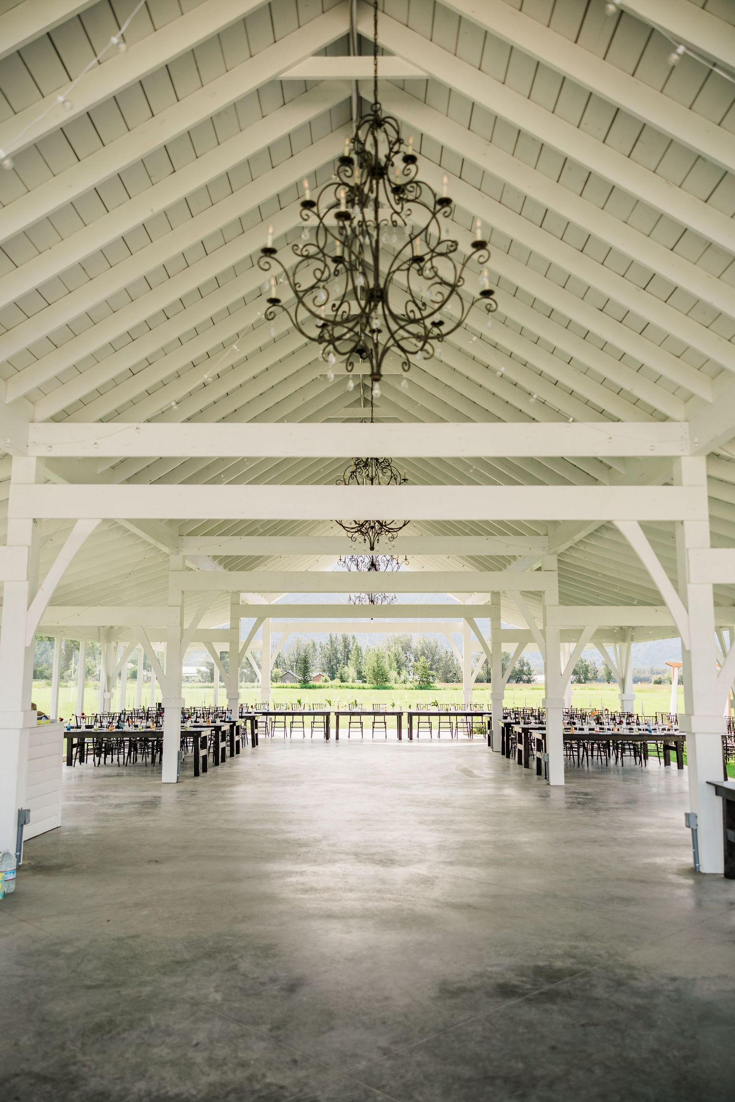 Large white pavilion venue interior with vaulted ceiling and chandeliers.
