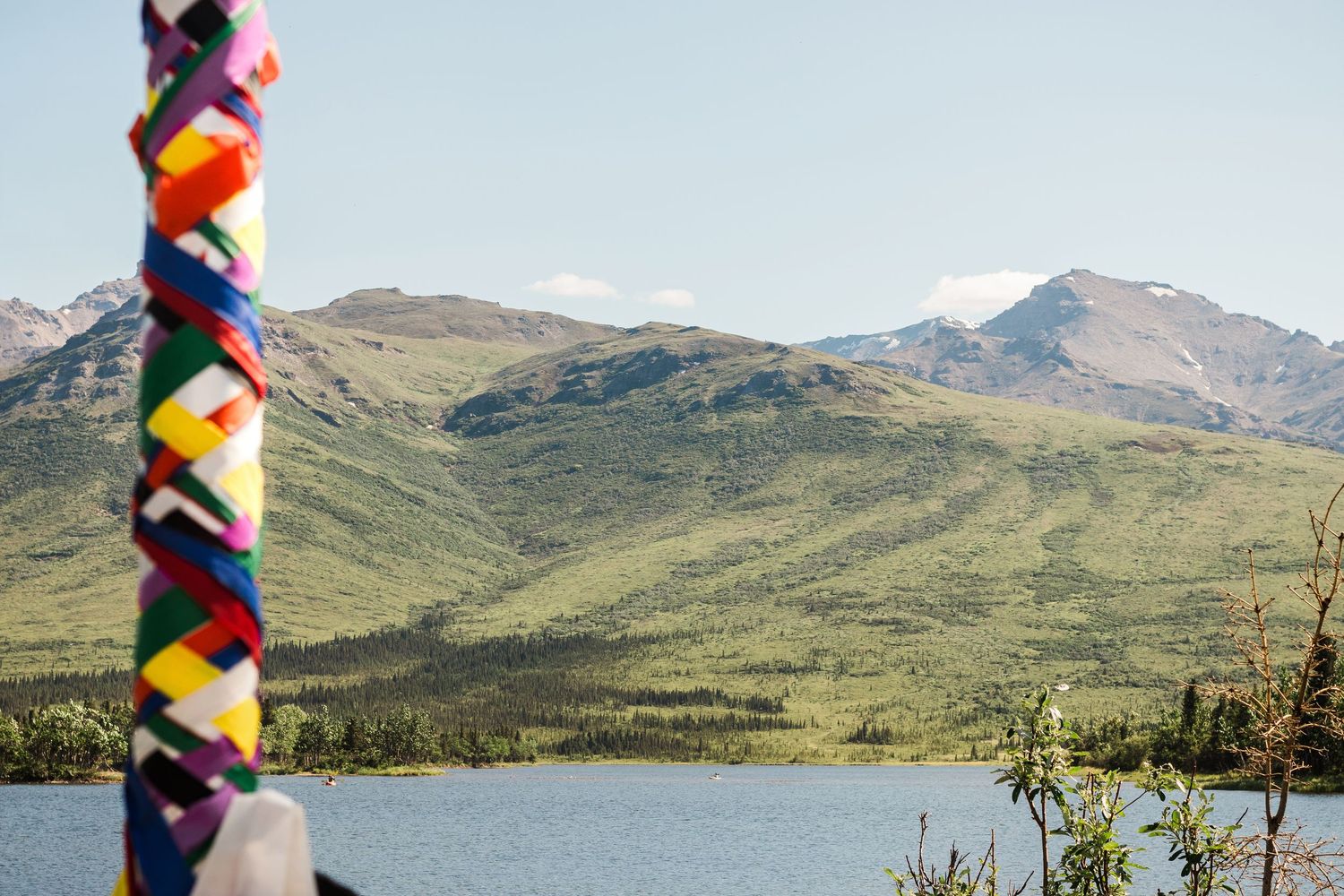 Colorful braided maypole ribbon against mountain landscape and lake backdrop.