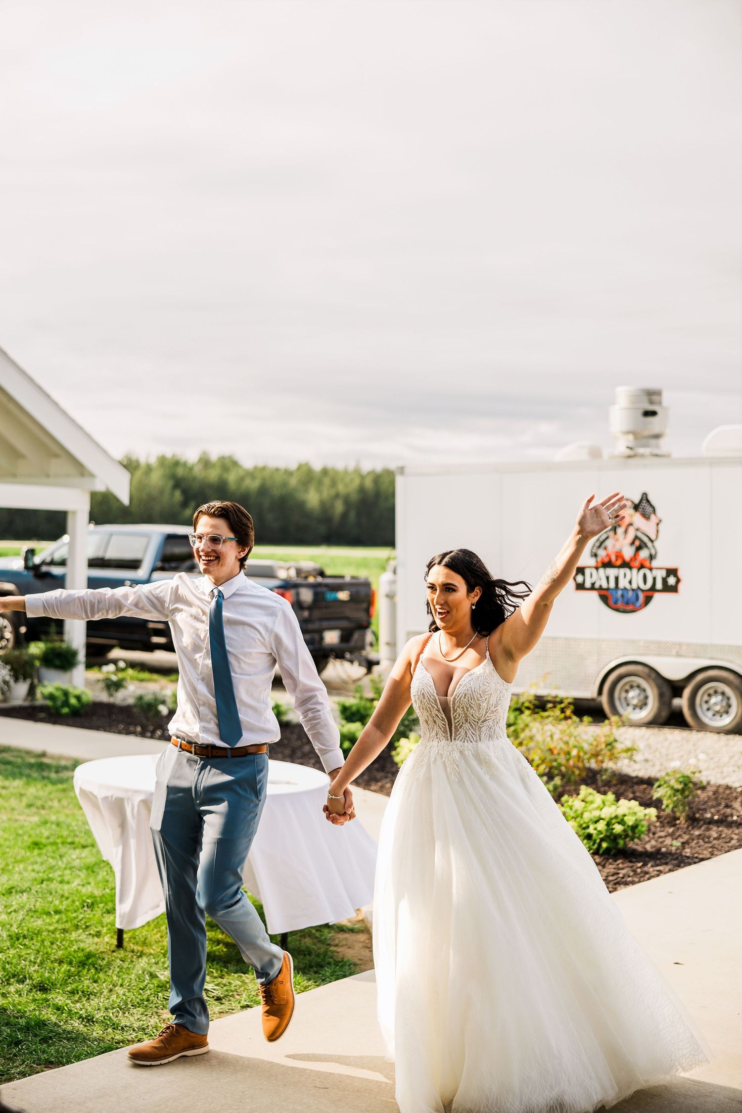 Newlyweds joyfully exit wedding venue holding hands while celebrating.