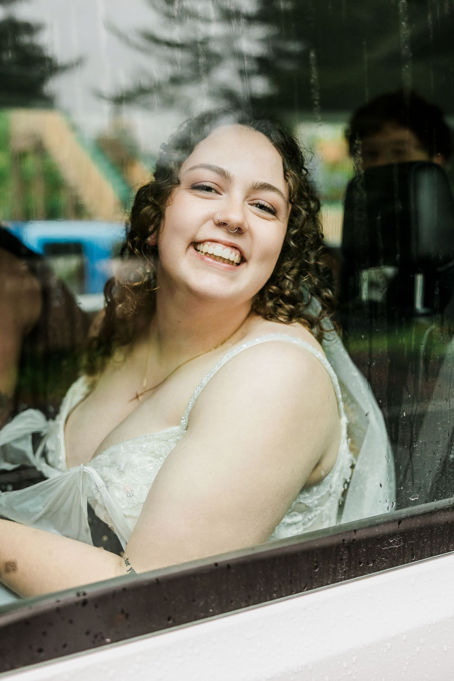 A person in white looks through a window with a joyful expression.