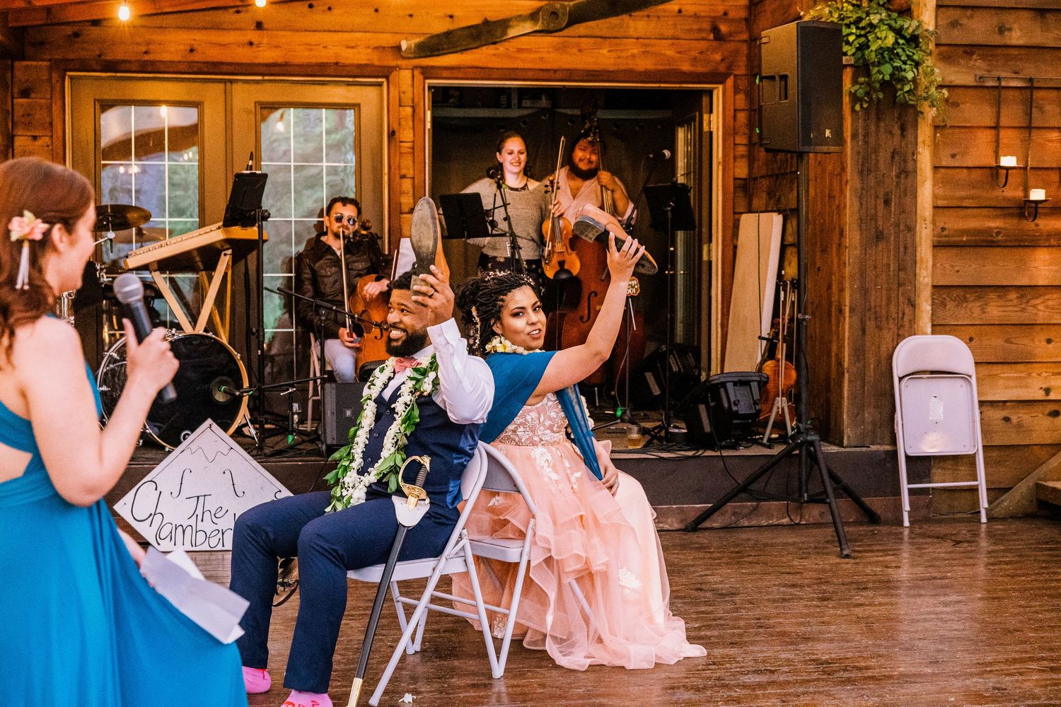Wedding celebration in a rustic wooden venue with musicians performing and guests enjoying the festivities.