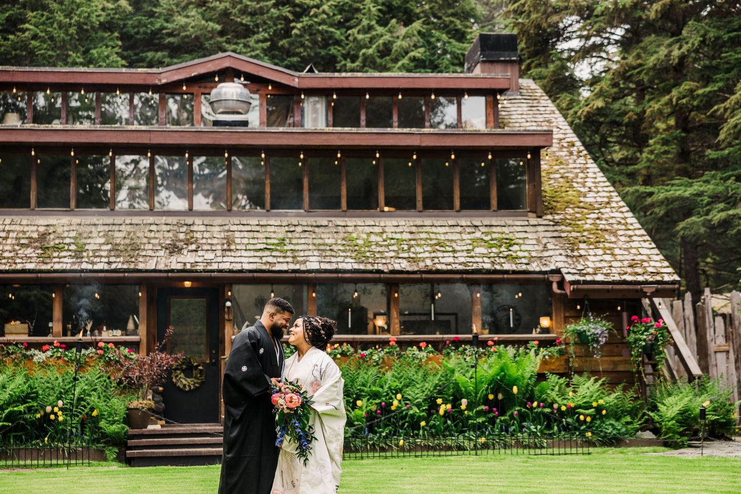 Panoramic view of a stone and wood lodge surrounded by lush Pacific Northwest landscaping.