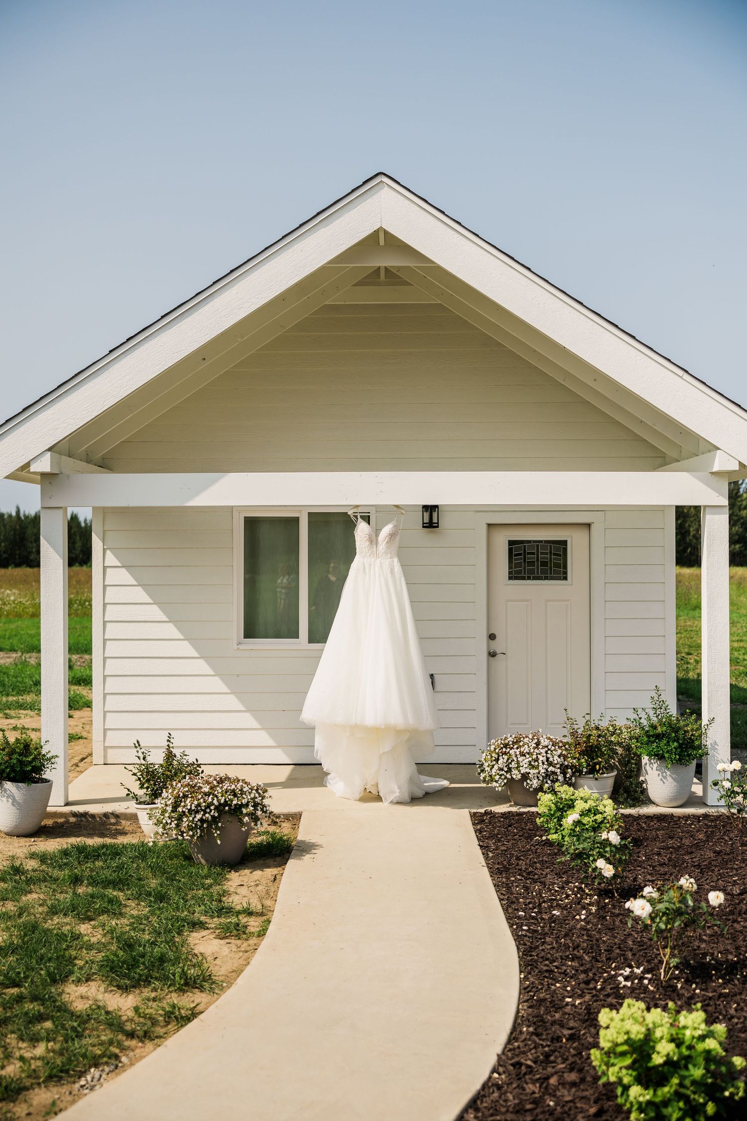 Modern white ranch-style house with concrete walkway and landscaped garden.