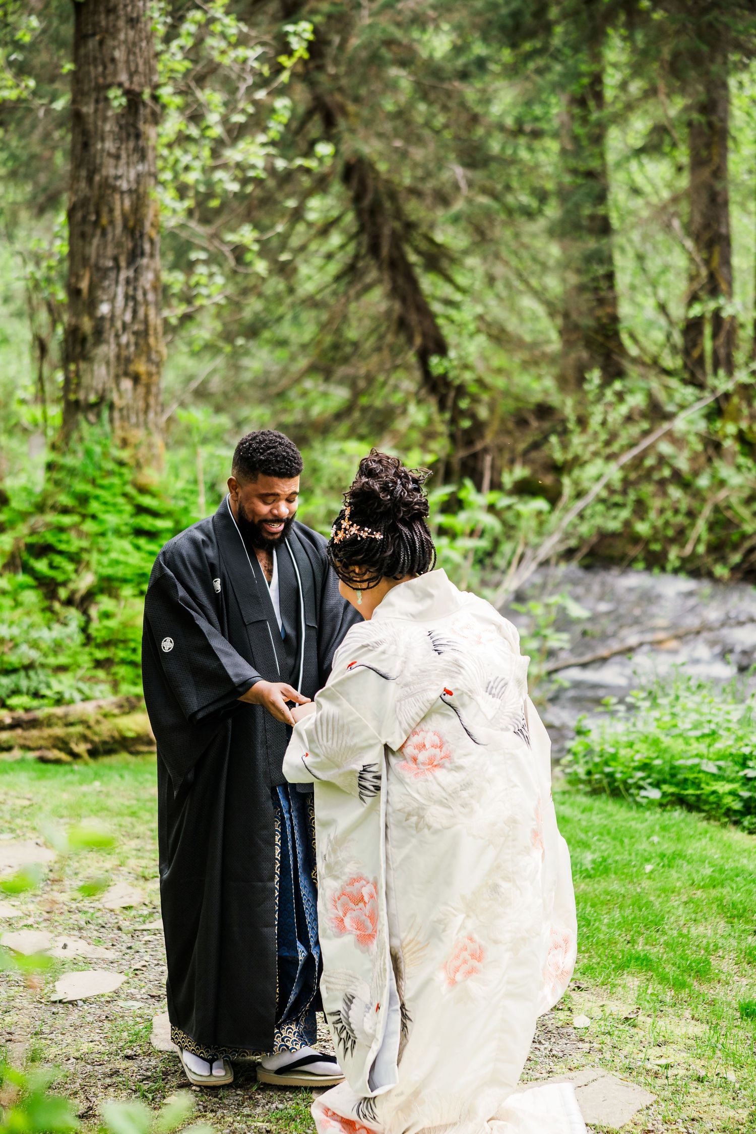 Couple holds hands during forest wedding ceremony wearing traditional Japanese wedding attire.