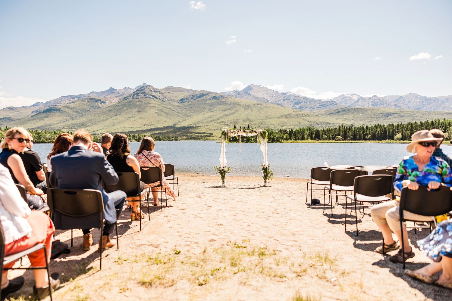 Lakeside wedding ceremony setup with mountain backdrop and rows of chairs.
